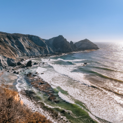 Early evening at Willow Creek Beach near Big Sur, California. View from the popular vista point off Cabrillo Highway along the Pacific Coast. Clear blue skies with bright sun reflection on the water.