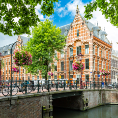 Typical canal side cityscape of Amsterdam, opposite from the 17th century HQ of the Dutch East India Company, now used by the University of Amsterdam