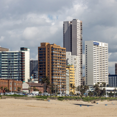 DURBAN, SOUTH AFRICA - DECEMBER 2, 2016: Empty quiet early morning Golden Mile beach front against comercial and residential buildings and blue cloudy sky in Durban, South Africa