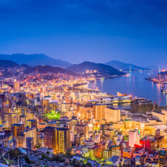 Nagasaki, Japan downtown skyline over the bay from above at night.