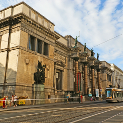BRUSSELS, BELGIUM - JUNE 29, 2010: The Royal Museum of Fine Arts with its stone columns and scenic sculptures makes the contrast with the modern tram, riding to its station, on June 29 in Brussels.