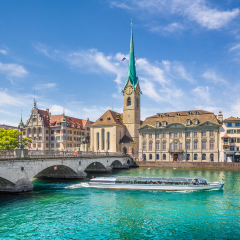Panoramic view of the historic city center of Zurich with famous Fraumunster Church and excursion boat on river Limmat on a sunny day with blue sky, Canton of Zurich, Switzerland