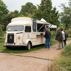 Oxford, United Kingdom - August 27, 2016: Coffee van in Oxford University Botanic Garden. Overcast weather with light rain. People queuing for coffee.