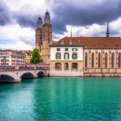 Beautiful view of historic city center of Zurich with famous Fraumunster Church and Munsterbucke crossing river Limmat on a sunny day with blue sky and clouds in summer, Canton of Zurich, Switzerland