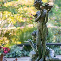 New York City, USA - September 24, 2016. Sculpture of a girl with a bird bath at the Burnett Memorial fountain. Natural setting with a bronze fountain statue in Conservatory Garden, Central Park.