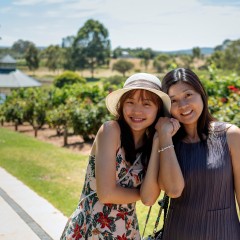 Beautiful young chinese asian long hair mother and daughter with hat and floral dress standing at one of the many wineries. Popular for wedding and corporate functions. Daily wine tasting tours.