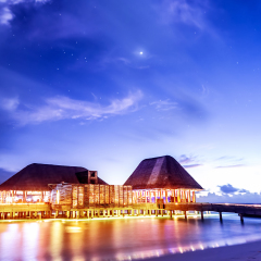 Beach restaurant glowing with bright lights in the night, romantic place for date on tropical island, summer holidays concept