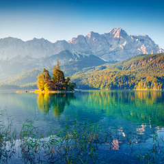Great summer sunrise on Eibsee lake with Zugspitze mountain range. Sunny outdoor scene in German Alps, Bavaria, Germany, Europe. Beauty of nature concept background.