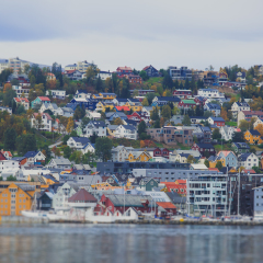 Beautiful super wide-angle panoramic aerial view of Tromso, Norway with harbor and skyline with scenery beyond the city, sunny summer day with blue sky 