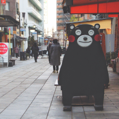 KUMAMOTO, JAPAN - JANUARY/4/2018: Kumamon, the local mascot of the earthquake devastated castle town smiles happily to greet visitors as they pass by in a small local market street.