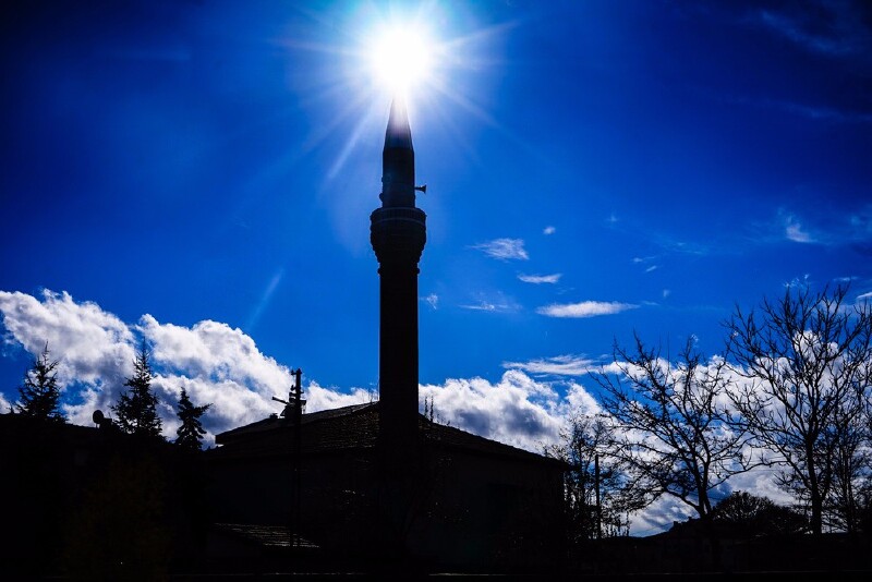 图,旁边,有一座宣礼塔顶上的太阳光芒四射