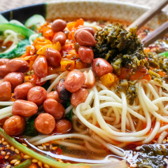 Spicy noodle soup with vegetables, herbs, peanuts and coriander, popular in Yunnan Province, shallow depth of field, China.