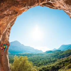 The girl climbs the rock. Training in a picturesque place. Fitness in nature. A woman overcomes a difficult climbing route. The climber trains on a natural relief in the form of an arch.