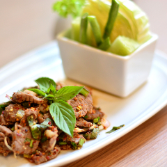 Thai Spicy meat or Larb neux salad. Traditional Thai food, chili and herbs. This food is popular in the north-east of the country (Isaan), in white plate on brown wood background, thai food, Tha
