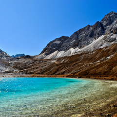 Unique colored Milk lake (approx. 4300m altitude) with blue sky and sharp mountains around it in Daocheng Yading Nature Reserve, Sichuan, China.  