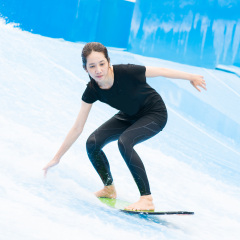 asia girl is playing surf borad with artificial waves house, action