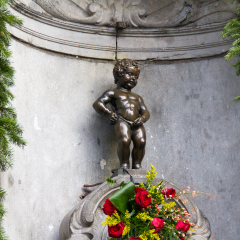Manneken Pis Of Bruxelles with red flowers