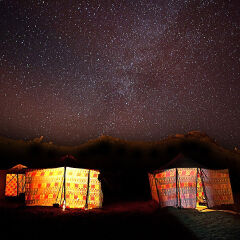 Illuminated Tents In Sahara Desert Against Constellations In Sky