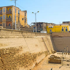 The massive wall shows the difference between the cultural layer of the Khnum Temple and modern housing of Esna, Egypt.