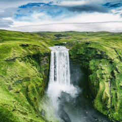 Iceland waterfall Skogafoss in Icelandic nature landscape. Famous tourist attractions and landmarks destination in Icelandic nature landscape on South Iceland. Aerial drone view of top waterfall.