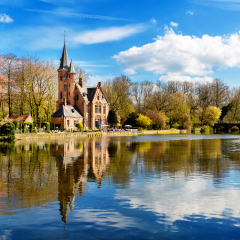 Minnewater lake panorama, reflection of gothic Flemish style building, cloudy blue sky, Bruges, Belgium