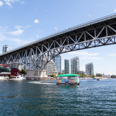 VANCOUVER - AUG. 16, 2017: Visitors to Granville Island taking the Aquabus water taxi across False Creek harbor with the Granville Street Bridge and Vancouver's Yaletown skyline in the background.