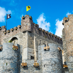 Medieval castle Gravensteen - Castle of the Counts with small windows surrounded by water in moat in Ghent, Flanders, Belgium.