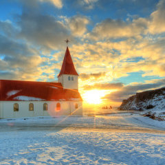 Typical red colored wooden church in Vik town, Iceland in winter. Sunrise light