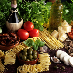 TABLE TOP FILLED WITH ASSORTED FRESH ITALIAN INGREDIENTS: BASIL,HERBS,TOMATOES,PARMESAN CHEESE,SLICED MOZZARELLA,DRIED MUSHROOMS,GREEN OLIVES,ASSORTED DRIED PASTA,SUNDRIED TOMATOES,OLIVE OIL 