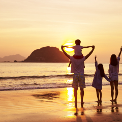 asian family standing on beach watching and enjoying the sunrise or sunset.