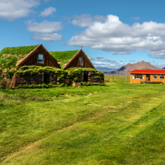 Traditional turf houses of Modrudalur farm settlement in Eastern Island of Fljotsdalsherad municipality. The green grassland  is at foreground, recent wooden hut is at background