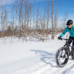 A beautiful woman cycling on a fat bike in the snow