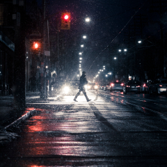 Winter snow storm with man crossing street. Silhouetted figure walking across downtown, urban, city street in heavy snowfall and traffic. Canadian winter night scene. Toronto, Ontario, Canada