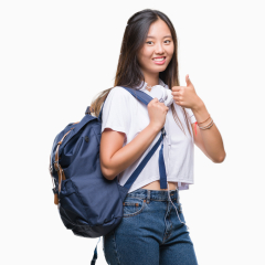 Young asian woman wearing backpack and headphones over isolated background happy with big smile doing ok sign, thumb up with fingers, excellent sign