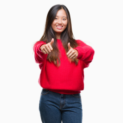 Young asian woman wearing winter sweater over isolated background approving doing positive gesture with hand, thumbs up smiling and happy for success. Looking at the camera, winner gesture.