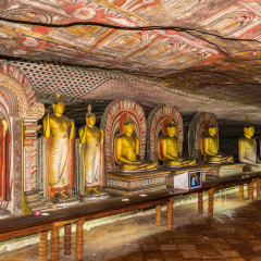 Rows of Buddha statues and frescos on the ceiling of the ancient Dambulla Cave Temple in Sri Lanka.