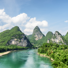 Scenic summer sunny landscape at Yangshuo County of Guilin, China. View of beautiful karst mountains and the Li River (Lijiang River) with azure water. Amazing green hills on blue sky background.