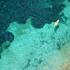 Aerial drone bird's eye view of kayaks cruising in tropical rocky seascape with turquoise and sapphire clear waters
