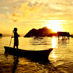 Silhouette of a kid paddling on a boat near Bajau Laut village in Maiga Island in Semporna, Sabah Borneo, Malaysia.