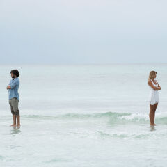 Couple standing apart in sea with backs turned toward each other