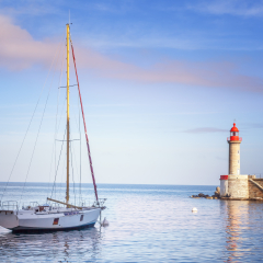 Beautiful white yacht on the sea, in the background of a lighthouse and sunset in gentle pink tones