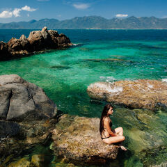 Woman Sitting On Rock In Sea