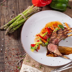 Kare of New Zealand lamb with vegetables Suites and Thai sauce. Restaurant food over wooden table.