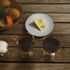 Wine and cheese testing, color grade WARM.
 Red wine, cheese, fruits on outdoor table. 
Compare the same image with color grade COLD
