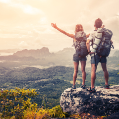 Hikers with backpacks relaxing on top of a mountain and enjoying the view of valley