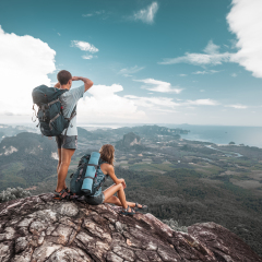 Hikers stand on top of a mountain and enjoy valley view