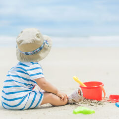 Asian 9 months baby boy playing on the sandy summer beach near the sea. Summer, Travel, Holiday concept.
