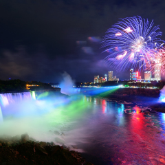 Niagara Falls lit at night by colorful lights with fireworks