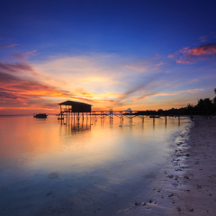 Amazing beautiful sunset with silhouette wooden jetty and coconut tree at Mantanani Island, Sabah, Borneo. Mantanani Island has long stretch of white sandy beaches and crystal clear water.