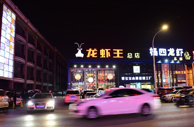 找到"龙虾王总店",迫不及待地跳下车,店铺的霓虹招牌在夜色中还挺显眼